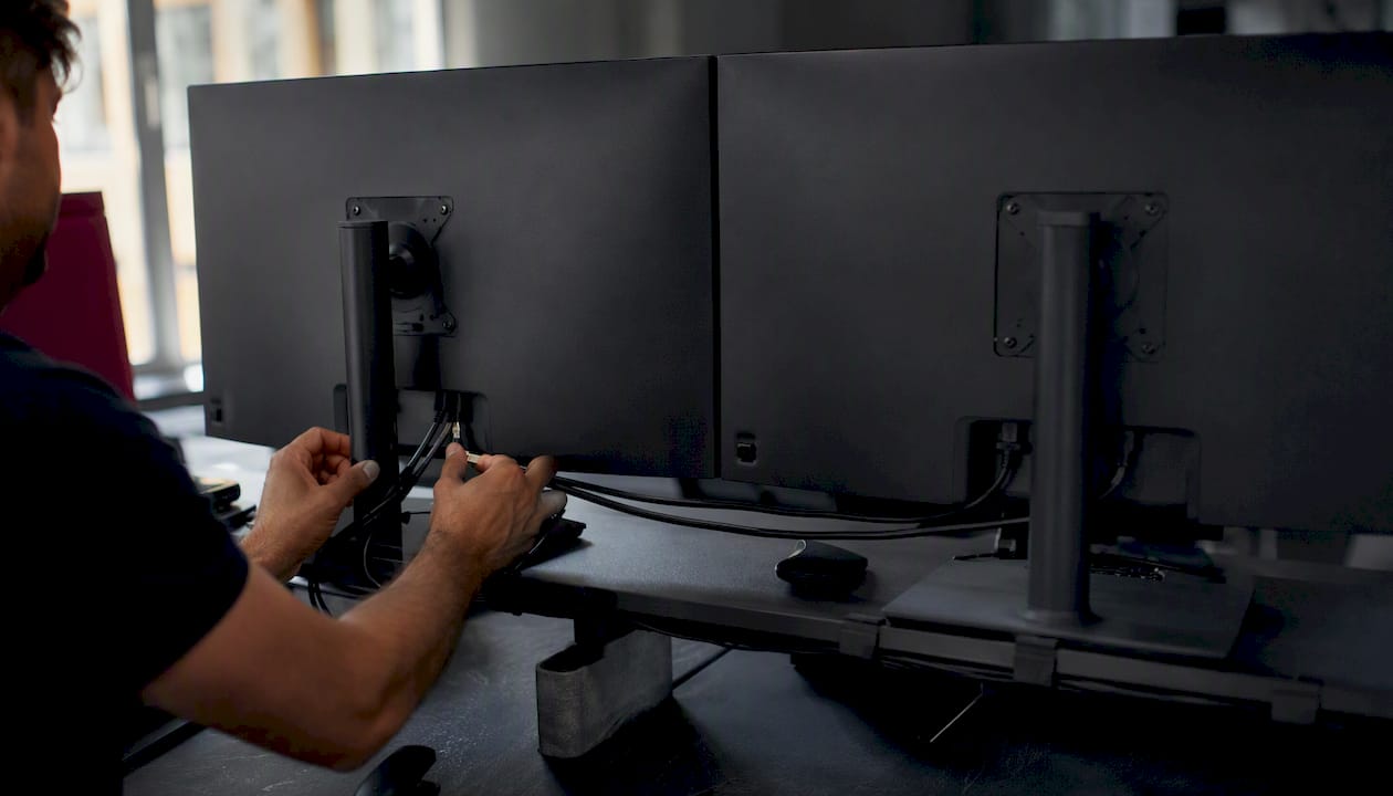 Hands switching cables behind trading monitors