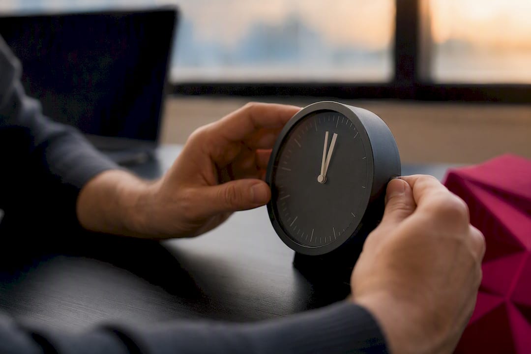 Hands adjusting desk clock for timing