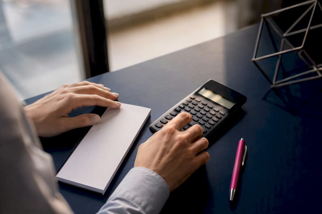 Hands calculating CFD swap costs with calculator