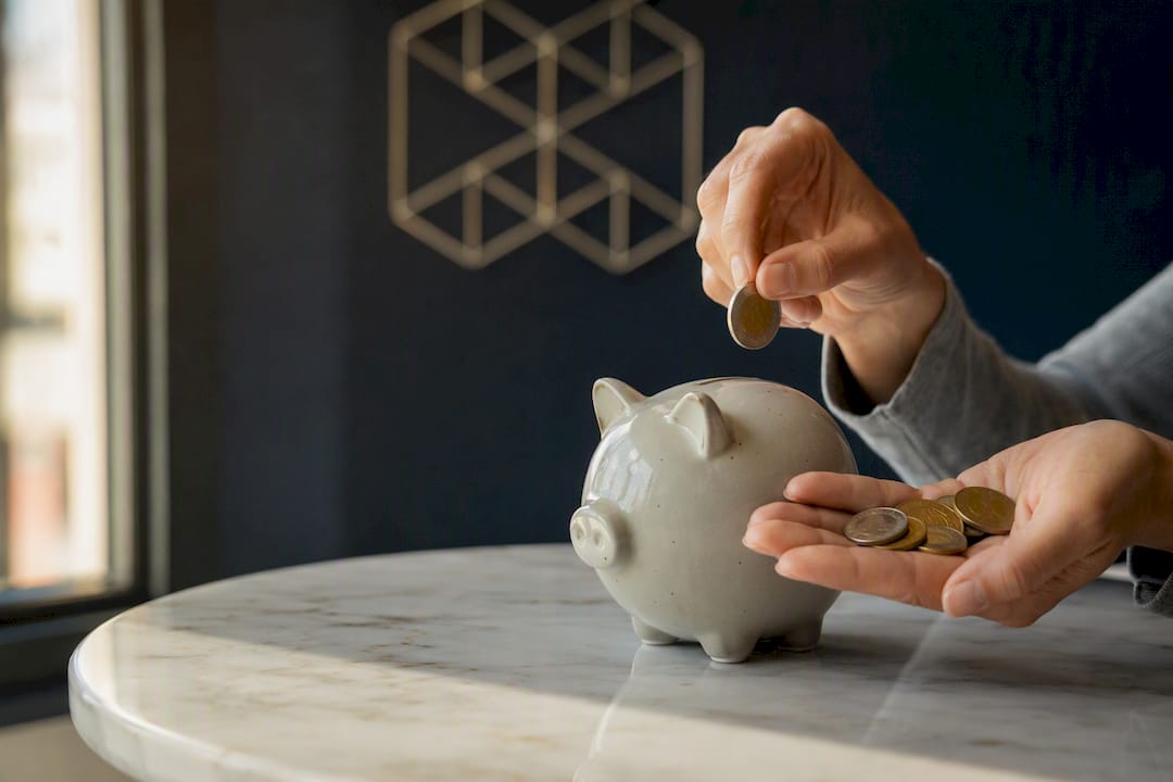Hands dropping coins into piggy bank